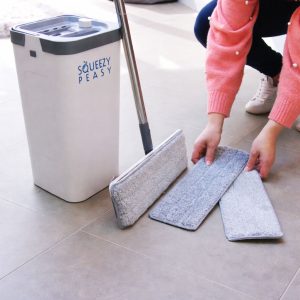Lightweight SqueezyPeasy Premium Compact & Lightweight Flat Mop and Bucket Cleaning System with a stainless-looking handle and a compact bucket, shown with several removable grey microfiber mop pads laid out on a tiled floor.