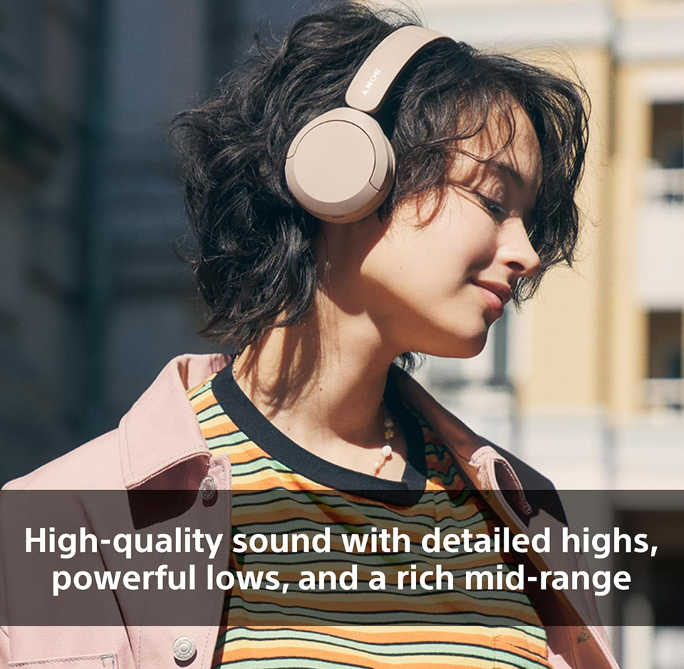 Person outdoors wearing beige Sony on‑ear wireless headphones, tilting their head slightly with eyes closed, showing the headphones’ cushioned earcups and adjustable headband in a lifestyle setting. High Quality Sound - Sony WH-CH520 Headphones