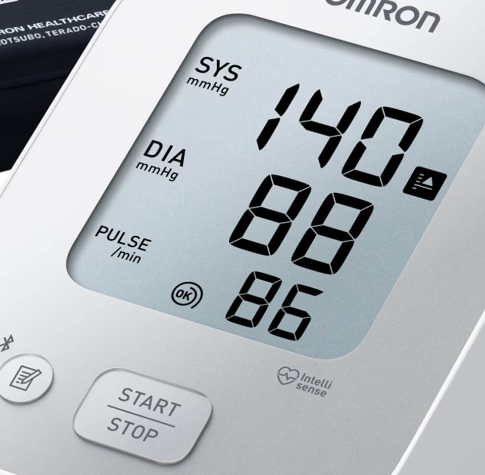 A close‑up of an Omron digital blood pressure monitor, showing readings of 140 systolic, 88 diastolic and a pulse of 86. The display is large and easy to read, with a prominent Start/Stop button beneath it.